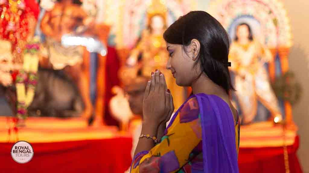 Interior of Dhakeshwari Temple in Dhaka, Bangladesh, during Durga Puja. Devotee in prayer attire.