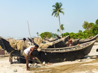 Fishermen are fixing their fishnets and fishing boats on Kuakata beach