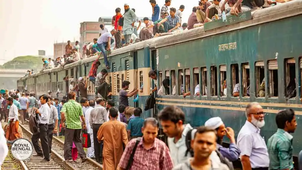 Crowded train station platform in Dhaka, Bangladesh. Passengers waiting on platform and train rooftop.