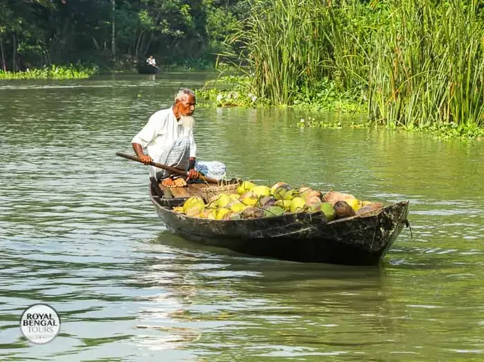 a farmer on a small boat piled with produce, traveling on a canal in Barisal, Bangladesh