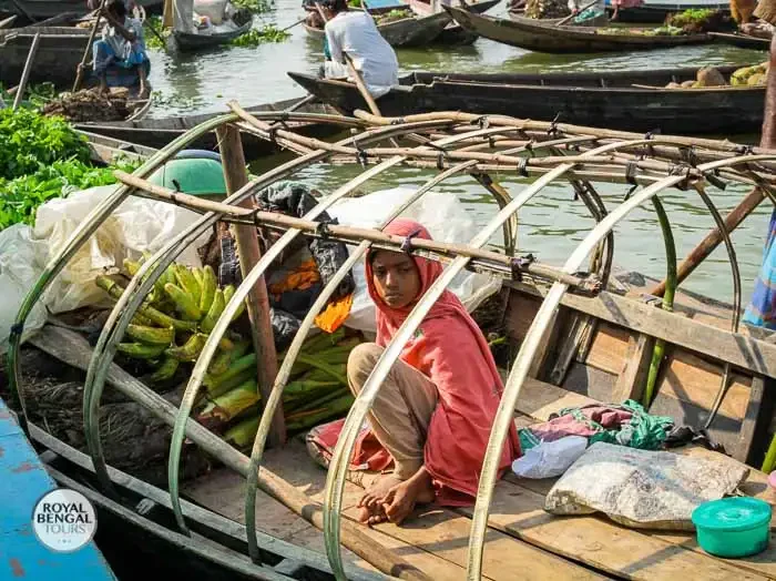 a traditional wooden boat overflowing with produce at a floating market in Barisal, Bangladesh