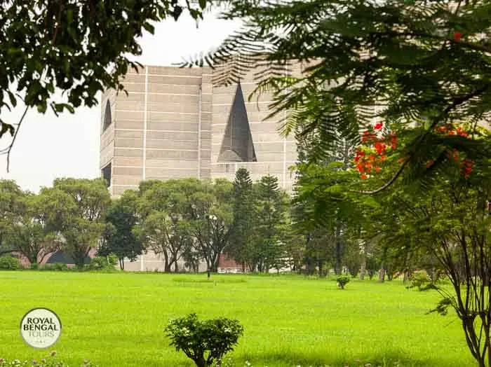 National Parliament House, Dhaka, partially visible through trees and greenery